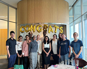 group of people posing in front of a gold congrats sign