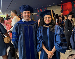 two people in caps and gowns posing for a graduation photo