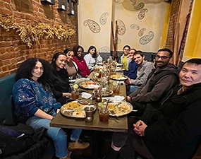 group of people at a table in a restaurant with food on plates in front of them
