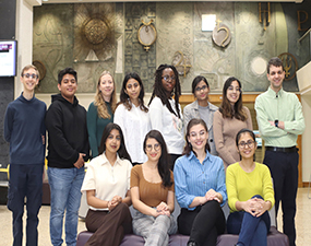 group of people posing in front of a textured wall, some sitting, some standing