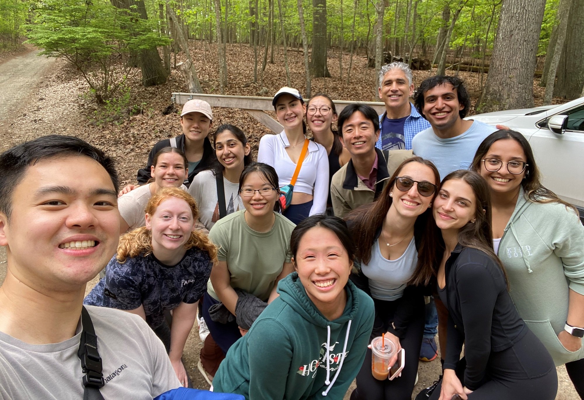 A group of smiling people take a selfie together while enjoying a wellness walk outdoors.